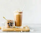 Eiskaffee mit gekochtem Kaffee, zubereitet im Thermomix, gekrönt mit Sahne. Daneben ein Glas mit Eiskaffee-Pulver.