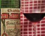 Ein Glas Rotwein neben einer Flasche Château La Grace Dieu, ein Saint-Émilion Grand Cru.
