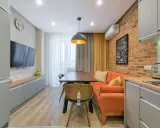 Idée pour aménager salon salle à manger 15m2 : canapé orange, table en bois, mur brique, cuisine moderne.