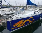 Voilier bleu orné d'un dragon jaune vif, prêt à naviguer. Les premiers 32 avis sont positifs.