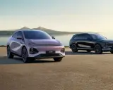 Deux voitures électriques, une rose et une noire, stationnées au bord de l'eau. Le modèle rose, un x peng, est plus proche.