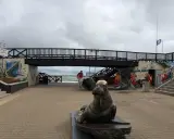 Pomnik foki i most nad plażą w Mielnie. Atrakcje dla turystów, ratownicy przygotowują sprzęt.