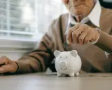 Un anciano deposita una moneda en una hucha, preparándose para la jubilación obligatoria.