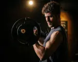 Mann mit lockigem Haar hebt Hantel im Fitnessstudio. Fokus auf Muskelaufbau und **bulking deutsch**.