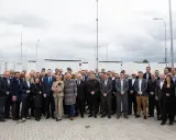 Grupa osób przed bateryjnymi magazynami energii, symbolizującymi rozwój polskiego stowarzyszenia magazynowania energii.