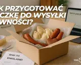 Jak przygotować paczkę z polskimi przysmakami do wysyłki? W pudełku pierogi, kiełbaski i piernik. Obok taśma, nożyczki i etykieta "Ship to England".