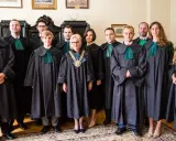 Grupa prawników w togach stoi w pomieszczeniu.