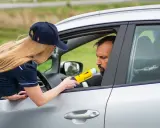 Policjantka mierzy kierowcy alkomatem, sprawdzając, czy nie przekroczył dopuszczalnego limitu promili.