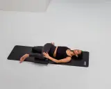 Frau mobilisiert mit Foam Roller die ISG-Region in Rückenlage.