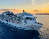 MSC Grandiosa, nave di dimensioni imponenti, solca il mare al tramonto, illuminata dalla luce dorata.