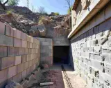 Bauarbeiten an einem Tunnel, der nach DIN 18532 errichtet wird. Mauern aus Betonsteinen und ein Eingang in den dunklen Tunnel.