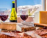 Dégustation de fromages et vin rouge, un aperçu de la gastronomie auvergnate avec vue sur les montagnes enneigées.