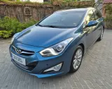 Niebieski Hyundai i40 1.7 CRDi na podjeździe z kostki brukowej, z tyłu ceglany mur porośnięty bluszczem.