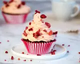 Ein köstlicher Red Velvet Muffin mit rosa Frosting und gefriergetrockneten Himbeeren, perfekt für ein Red Velvet Muffins Rezept.
