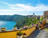 Widok na jezioro i zielone wzgórza z kolorowymi domami w Castel Gandolfo.