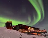 Abisko Sky Station badar i norrskenets gröna ljus. En magisk natt i svenska Lappland.