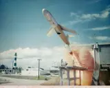 Rakete startet von Plattform, Rauch steigt auf. Ein Leuchtturm im Hintergrund. Eine Szene, die an die Kubakrise erinnert, zusammenfassend.