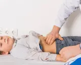 Médico examina el abdomen de un niño con posible gastroenteritis.