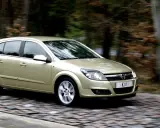 Złoty Opel Astra 1.7 CDTI w ruchu, na tle rozmytego lasu.