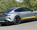 Silbernes Xiaomi Auto mit gelben Akzenten und Spoiler, das auf einer Straße parkt.