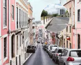 Bunte Häuser säumen eine steile Straße in Lissabon. Ein Kreis zeigt einen Parkplatz mit Markierungen, der eine Option für Parken Lissabon darstellt.