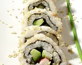 En närbild på en california roll med avokado och krabba, strödd med sesamfrön.