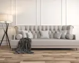 Divano imbottito grigio con cuscini a righe e coperta geometrica. La luce soffusa di una lampada da terra illumina la scena, dimostrando come grigio e beige stiano bene insieme.