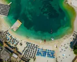 Widok z lotu ptaka na plażę z leżakami, parasolami i turkusową wodą.