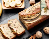 Un delicioso banana bread casero, con trozos de chocolate y plátano en rodajas, junto a nueces y canela.