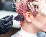 Aplicando tinte rosa en el cabello. Si te manchas, aprende como quitar el tinte de la piel.