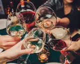 Ludzie wznoszą toasty winem. Pamiętaj o odpowiedzialnym spożywaniu alkoholu, zwłaszcza gdy rozważasz antykoncepcję.