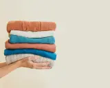 Hände halten einen Stapel bunter Pullover. Eine gute Idee für waschmittel ersatz, wenn man die Kleidung schonend behandeln möchte.