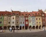 Kolorowe kamienice na Starym Rynku w Poznaniu, gdzie kwitnie rozrywka. Ludzie spacerują po bruku, podziwiając architekturę.