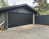 Nyinstallerad svart garageport montering på ett mörkt garage.