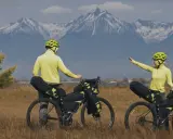 Para szykuje się na przygodę bike packing. W tle majestatyczne, ośnieżone góry.