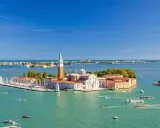 Vue aérienne de Venise, le campanile San Giorgio Maggiore se dresse fièrement sur son île, entouré d'eaux turquoise et de voiliers.