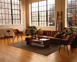 Przytulny salon w stylu loft aranżacje. Brązowa skórzana kanapa, drewniane meble i duże okna tworzą ciepłą atmosferę.