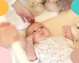 Un bebé despierto en su cuna, con una mano acariciándole la cabeza. Parece que mi bebe tarda mucho en dormirse.