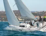 Bateau à voile "First 27" en pleine navigation, équipage concentré sur le plan d'eau bleu.