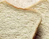 Zwei Scheiben Weißbrot liegen auf einem Holzbrett. Die Frage "wie viel Kalorien hat eine Scheibe Toast?" beschäftigt viele.