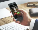 Dłoń trzyma smartfon z ekranem połączenia. Dowiedz się, jak odsłuchać pocztę głosową plus, gdy dzwoni telefon.