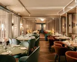 Elegant dining room at Hasselbacken restaurang, Stockholm. Tables set with glassware and cutlery, plush seating, and soft lighting create a sophisticated atmosphere.