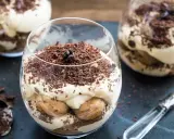 Pyszne tiramisu bez pieczenia w szklankach, udekorowane startą czekoladą i ziarnami kawy. Idealne na deser.