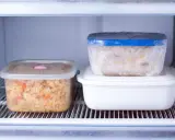 Zwei Behälter mit vorbereiteten Gerichten zum Einfrieren stehen im Kühlschrank. Einer enthält Reis mit Gemüse, der andere eine cremige Speise.
