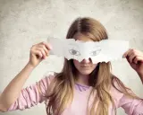 Dziewczynka z papierem zakrywającym oczy, na którym narysowano oczy. Czyżby to była mitomanka, która ukrywa swoje prawdziwe spojrzenie?