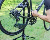 Rowerzysta zakłada łańcuch w rowerze z przerzutkami. Pokazano tylną przerzutkę, kasetę i korbę.