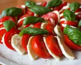 Kolorowe pomidory z mozzarellą i listkami bazylii, doprawione pieprzem, tworzą apetyczną sałatkę Caprese.