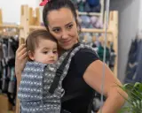 Mama wybiera jakie nosidełko dla 5 miesięcznego niemowlaka. Dziecko w nosidle z wzorem.