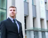 Mężczyzna w garniturze przed nowoczesnym budynkiem.