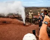 Touristen bestaunen im Nationalpark Timanfaya eine Dampf-Demonstration. Ein Führer gießt Wasser in ein Loch, das sofort zu Dampf wird.